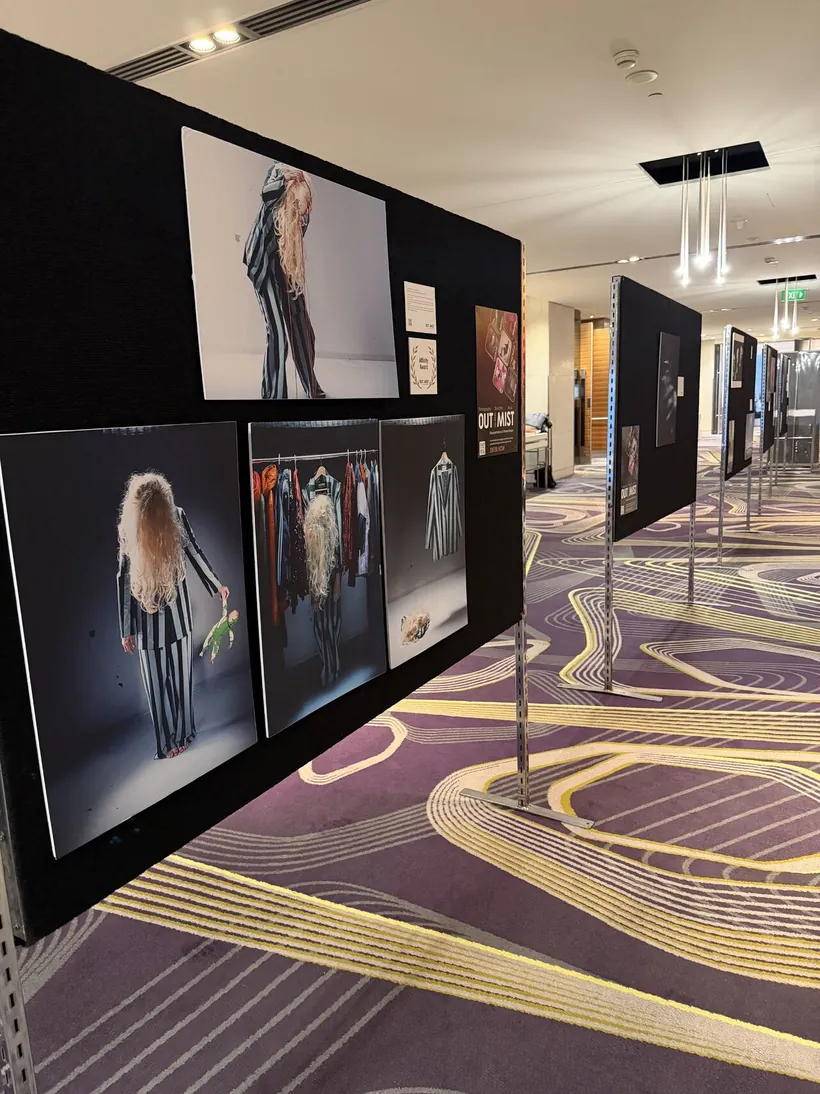 Close-up of framed Out From The Mist photographs, including striking portraits, on a black display wall